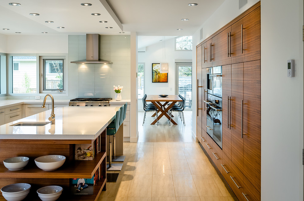 Moderne Küche in L-Form mit Unterbauwaschbecken, flächenbündigen Schrankfronten, hellbraunen Holzschränken, Küchenrückwand in Blau und Küchengeräten aus Edelstahl in Vancouver