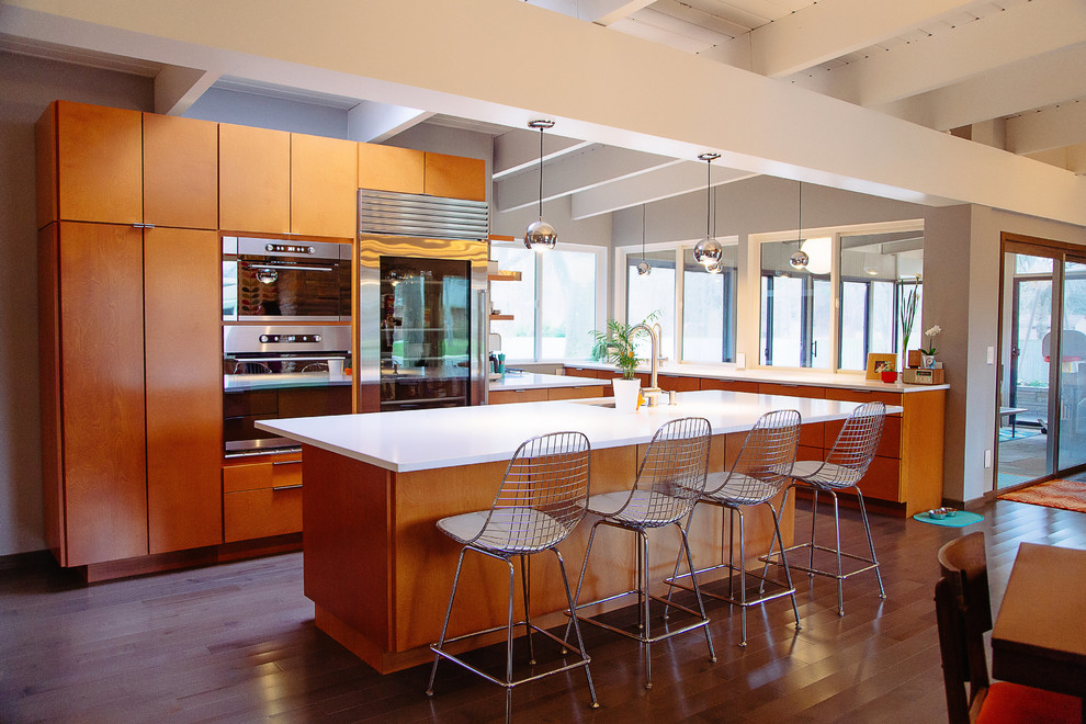 Inspiration for a mid-sized 1960s medium tone wood floor open concept kitchen remodel in Grand Rapids with an undermount sink, flat-panel cabinets, medium tone wood cabinets, stainless steel appliances and an island