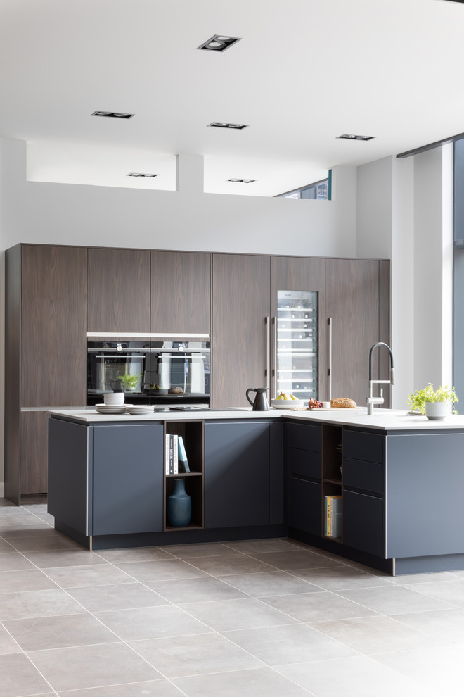 Moderne Küche mit flächenbündigen Schrankfronten, blauen Schränken, schwarzen Elektrogeräten, grauem Boden und weißer Arbeitsplatte in West Midlands
