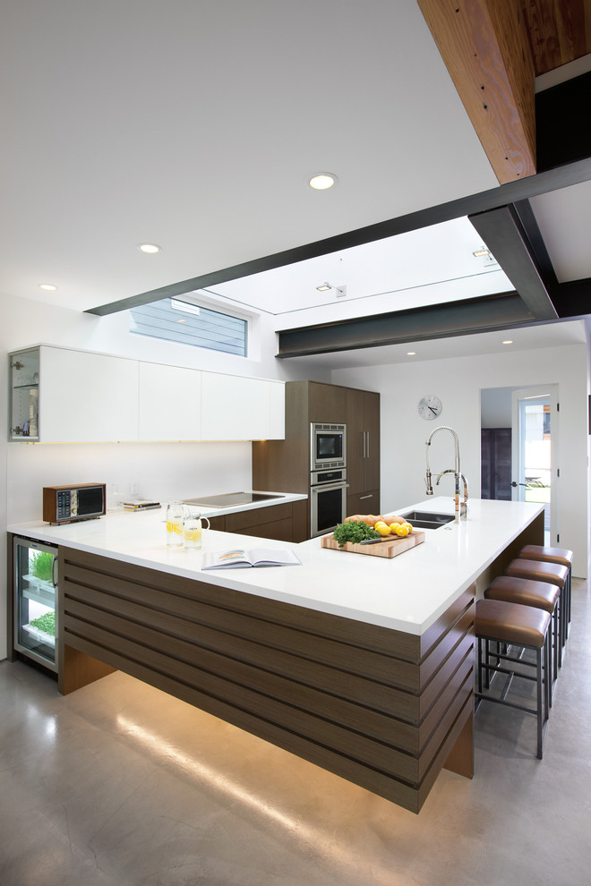 Moderne Küche in U-Form mit flächenbündigen Schrankfronten, dunklen Holzschränken, Küchengeräten aus Edelstahl, Halbinsel und Betonboden in Vancouver
