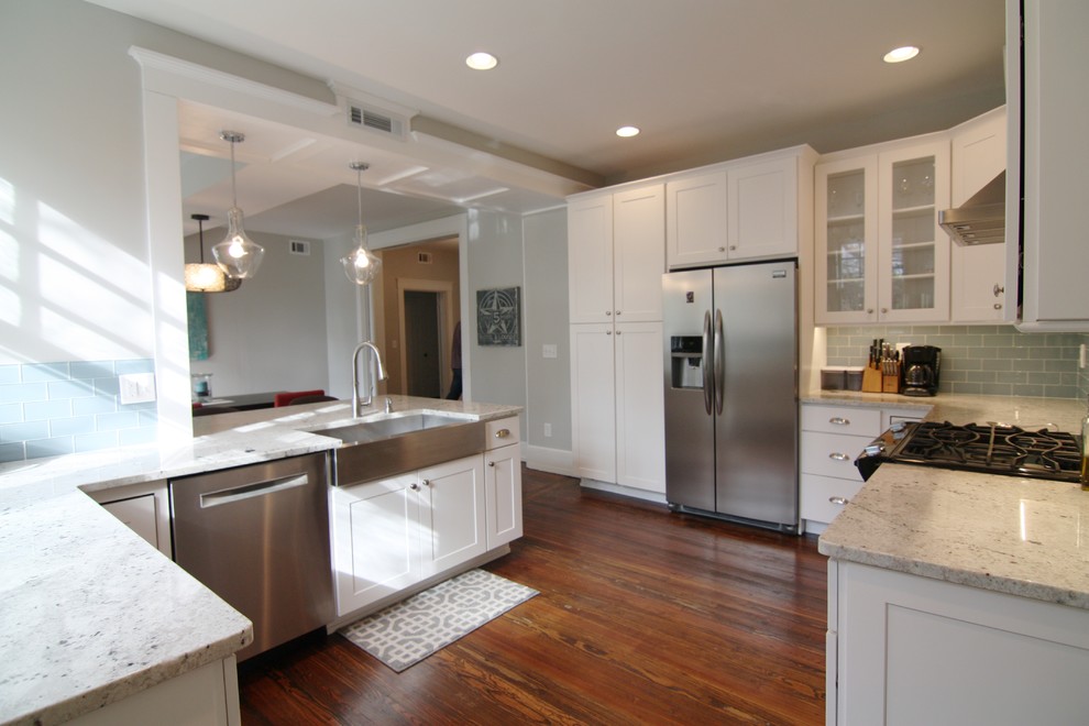 Eat-in kitchen - mid-sized craftsman l-shaped medium tone wood floor eat-in kitchen idea in Atlanta with a farmhouse sink, shaker cabinets, white cabinets, granite countertops, blue backsplash, glass tile backsplash, stainless steel appliances and a peninsula