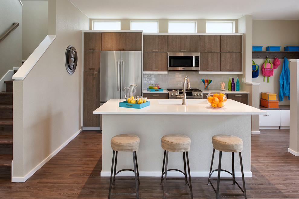 Zweizeilige Moderne Küche mit flächenbündigen Schrankfronten, dunklen Holzschränken, Küchenrückwand in Grau, Rückwand aus Metrofliesen, Küchengeräten aus Edelstahl, dunklem Holzboden und Kücheninsel in Denver