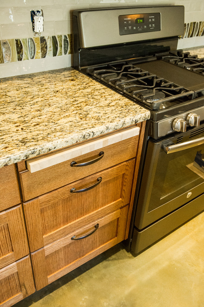 Foto på ett litet amerikanskt linjärt kök med öppen planlösning, med en undermonterad diskho, skåp i mellenmörkt trä, granitbänkskiva, stänkskydd i keramik, betonggolv, en köksö och grått golv