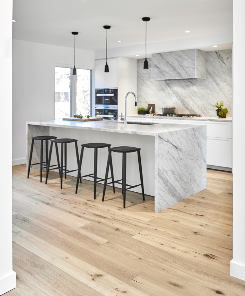 Medium sized contemporary l-shaped kitchen/diner in Toronto with a submerged sink, flat-panel cabinets, white cabinets, marble worktops, multi-coloured splashback, marble splashback, black appliances, light hardwood flooring, an island, brown floors and multicoloured worktops.