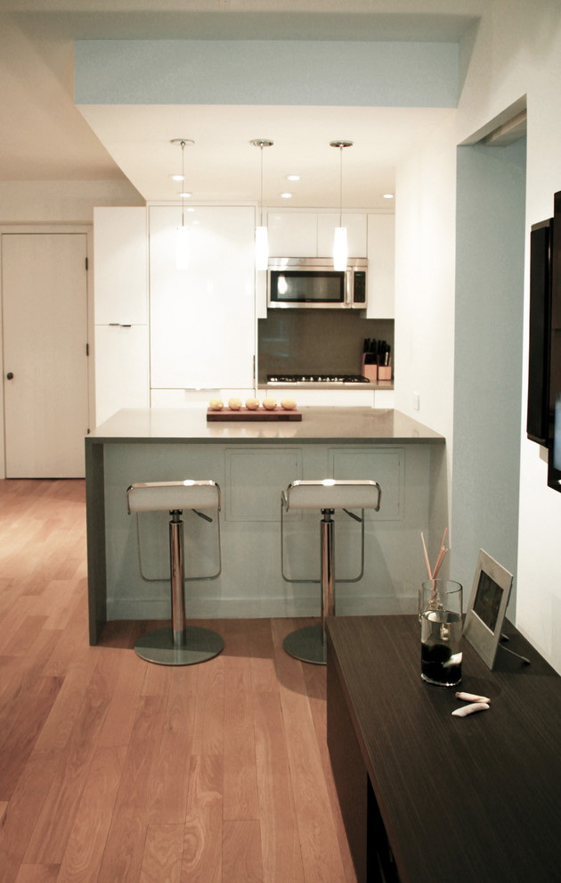 Foto di una piccola cucina minimalista con ante lisce, ante bianche, top in superficie solida, paraspruzzi grigio e elettrodomestici in acciaio inossidabile