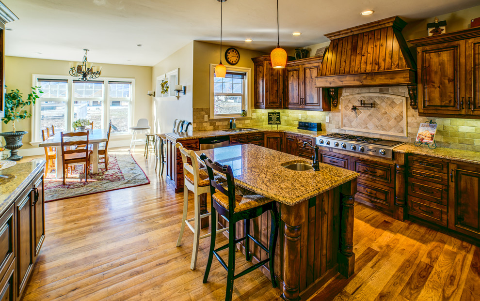 Exempel på ett stort lantligt kök, med en nedsänkt diskho, luckor med upphöjd panel, skåp i slitet trä, granitbänkskiva, vitt stänkskydd, rostfria vitvaror, mellanmörkt trägolv och en köksö
