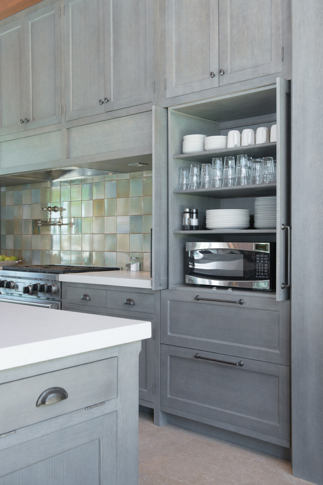 Amerikansk inredning av ett mycket stort kök, med grå skåp, blått stänkskydd, stänkskydd i keramik, integrerade vitvaror, en köksö och luckor med infälld panel