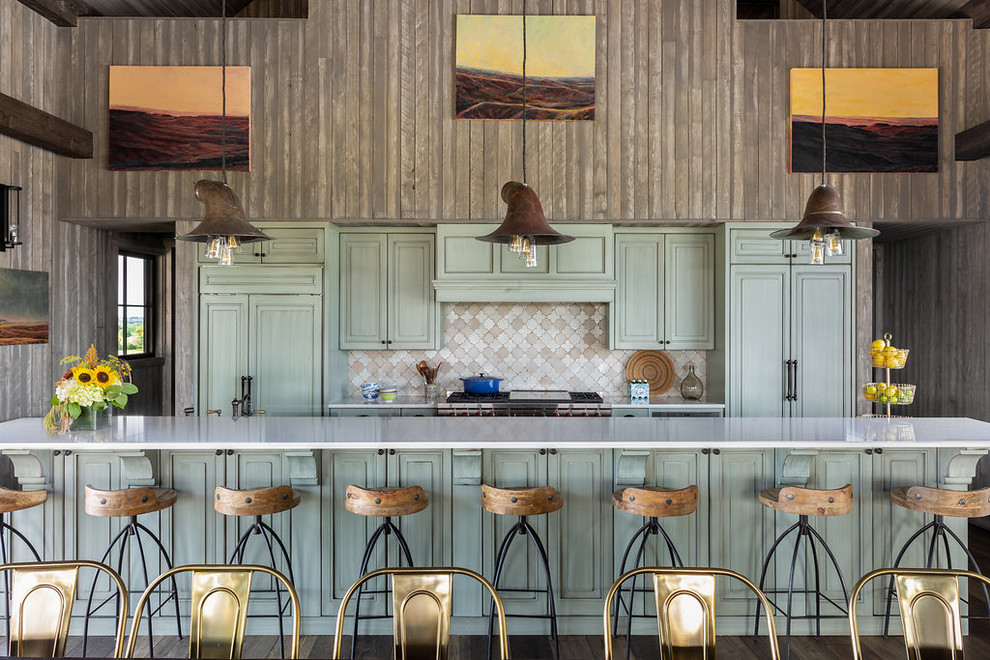 Diseño de cocina comedor campestre con puertas de armario verdes, salpicadero multicolor, electrodomésticos con paneles, suelo de madera oscura, una isla, suelo marrón y encimeras blancas