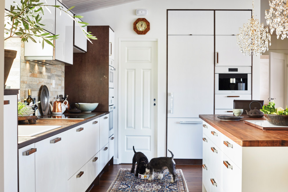 Inspiration for a medium sized scandinavian l-shaped open plan kitchen in Cheshire with a built-in sink, glass-front cabinets, white cabinets, wood worktops, grey splashback, stone tiled splashback, stainless steel appliances, vinyl flooring, an island, brown floors and brown worktops.