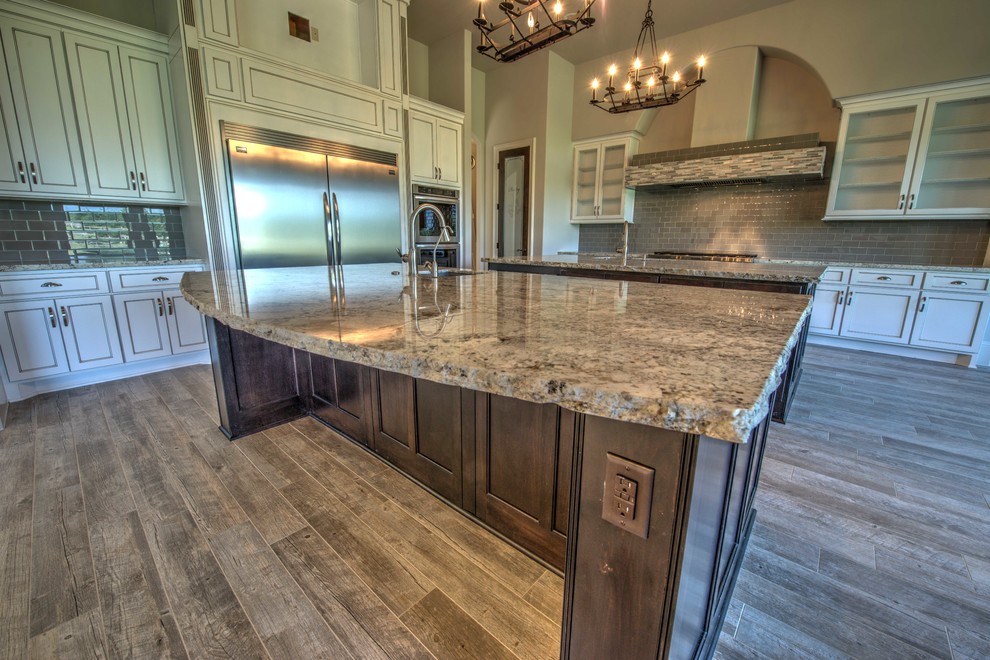 Example of a huge tuscan u-shaped ceramic tile open concept kitchen design in Houston with an undermount sink, shaker cabinets, beige cabinets, granite countertops, gray backsplash, ceramic backsplash, stainless steel appliances and two islands
