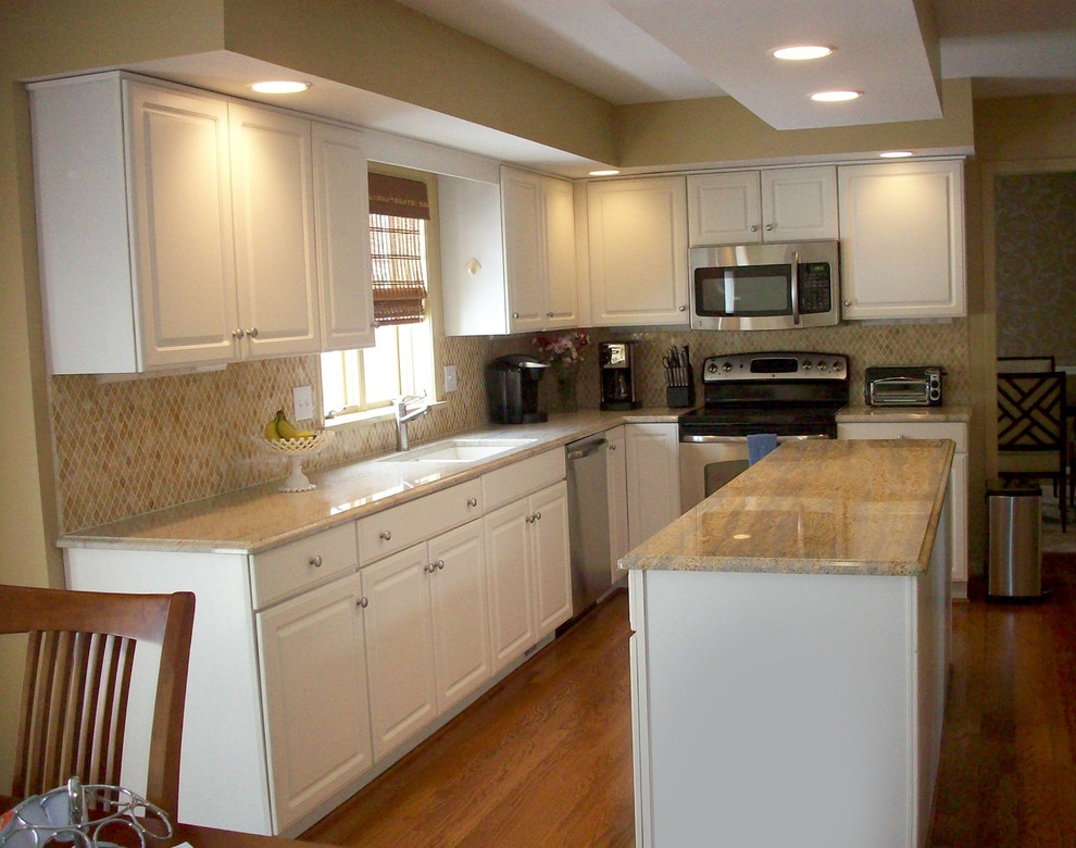 Example of a mid-sized transitional l-shaped medium tone wood floor eat-in kitchen design in New York with a single-bowl sink, raised-panel cabinets, white cabinets, granite countertops, yellow backsplash, mosaic tile backsplash, stainless steel appliances and an island