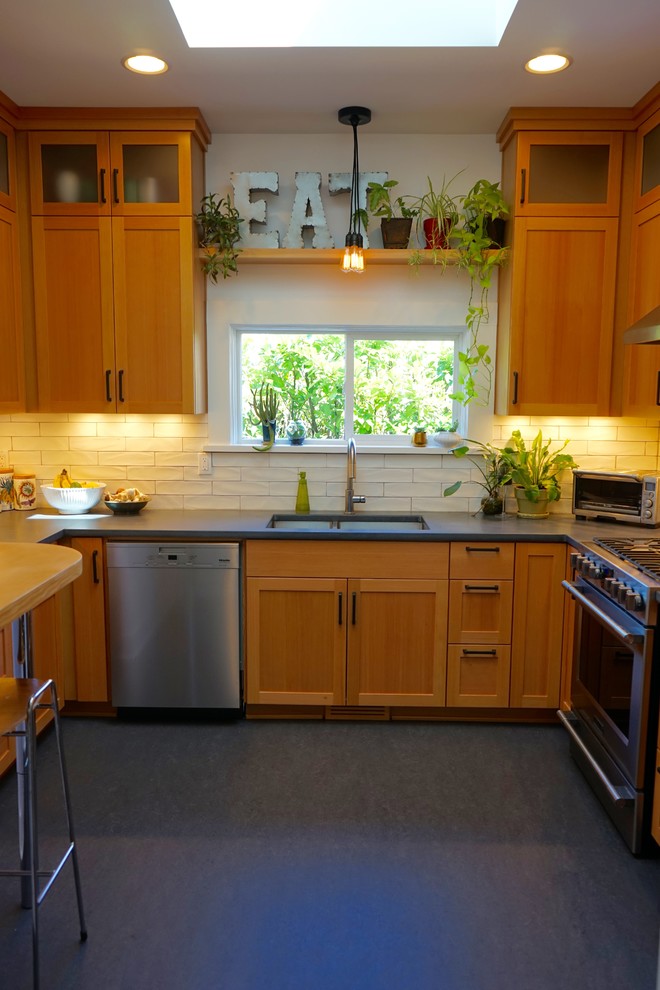 Bild på ett avskilt, litet funkis u-kök, med en undermonterad diskho, skåp i shakerstil, skåp i ljust trä, bänkskiva i betong, vitt stänkskydd, stänkskydd i keramik, rostfria vitvaror och linoleumgolv