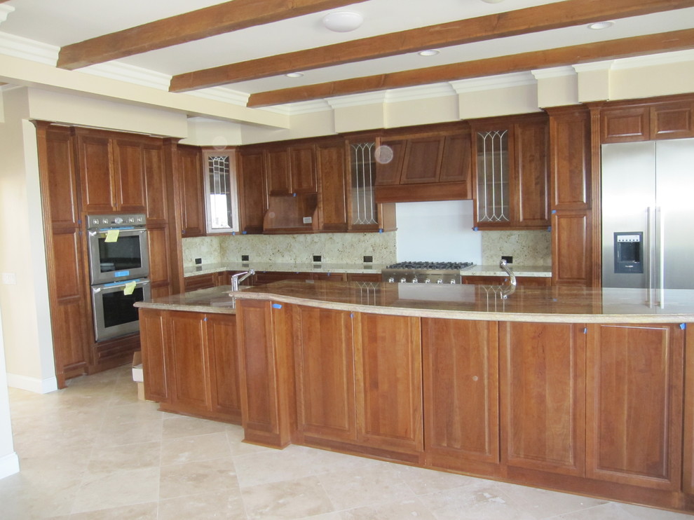 Mid-sized elegant l-shaped travertine floor eat-in kitchen photo in Los Angeles with an undermount sink, beaded inset cabinets, medium tone wood cabinets, granite countertops, beige backsplash, stone slab backsplash, stainless steel appliances and an island