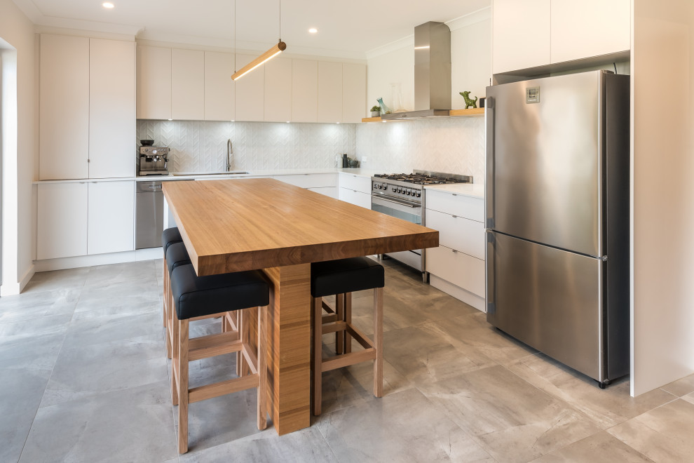 Mid-sized urban l-shaped cement tile floor and gray floor eat-in kitchen photo in Adelaide with an undermount sink, flat-panel cabinets, white cabinets, quartz countertops, white backsplash, mosaic tile backsplash, stainless steel appliances, an island and white countertops