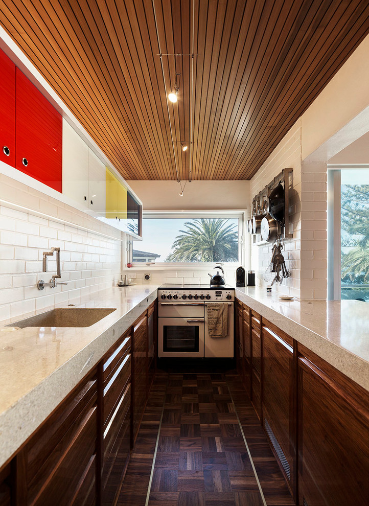Small mid-century modern galley dark wood floor and brown floor eat-in kitchen photo in Auckland with a drop-in sink, recessed-panel cabinets, dark wood cabinets, terrazzo countertops, white backsplash, brick backsplash, white appliances and no island