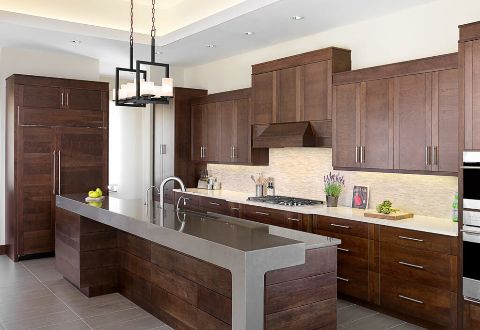 Example of a trendy kitchen design in Vancouver with dark wood cabinets, beige backsplash, paneled appliances and an island