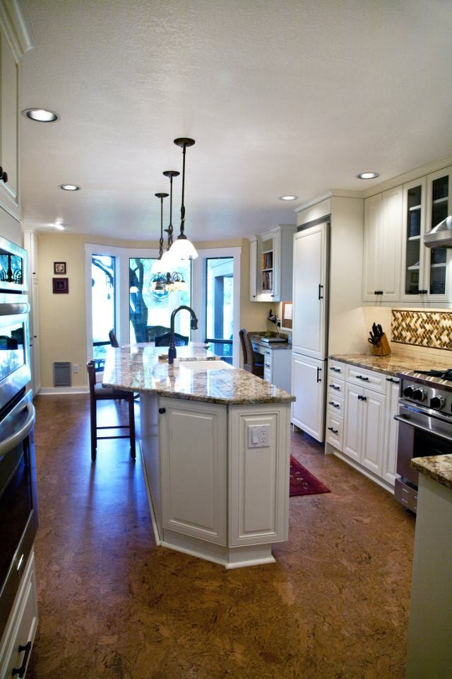 Eat-in kitchen - large traditional l-shaped concrete floor eat-in kitchen idea in Seattle with a farmhouse sink, raised-panel cabinets, white cabinets, granite countertops, multicolored backsplash, mosaic tile backsplash, paneled appliances and an island