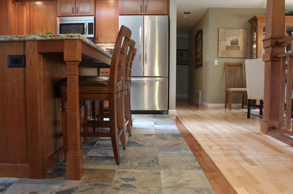 Immagine di un cucina con isola centrale stile americano con lavello sottopiano, ante in stile shaker, ante in legno scuro e pavimento in ardesia