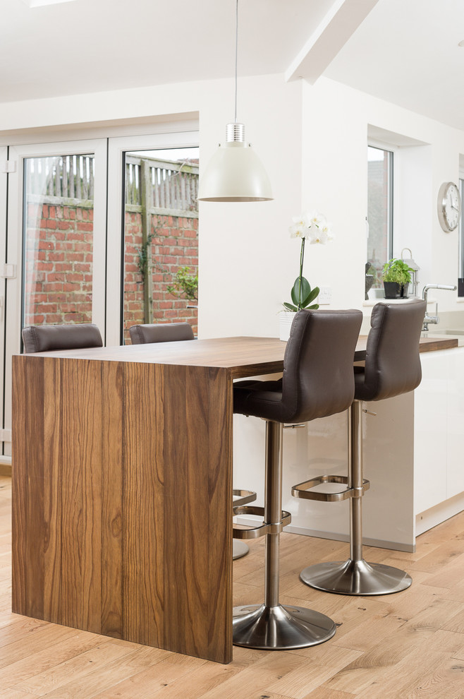 Example of a trendy kitchen design in Other with flat-panel cabinets, white cabinets, wood countertops and a peninsula