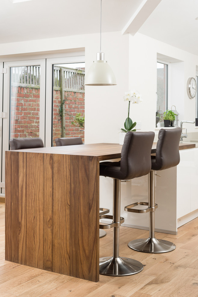 Contemporary kitchen in Other with flat-panel cabinets, white cabinets, wood worktops and a breakfast bar.