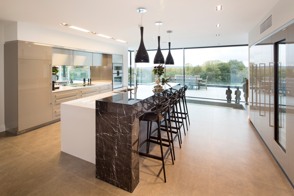 Design ideas for a large contemporary galley open plan kitchen in London with a submerged sink, marble worktops, mirror splashback, stainless steel appliances, an island and white worktops.