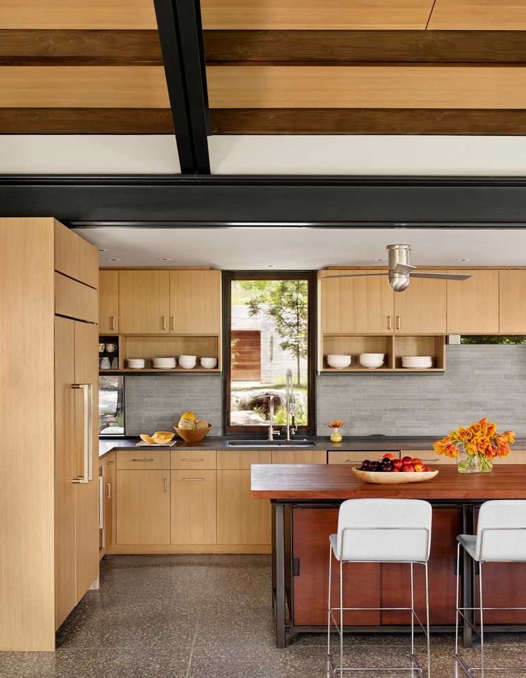 Idée de décoration pour une cuisine encastrable design en bois clair avec un évier encastré, un placard à porte plane, une crédence grise, îlot et fenêtre au-dessus de l'évier.