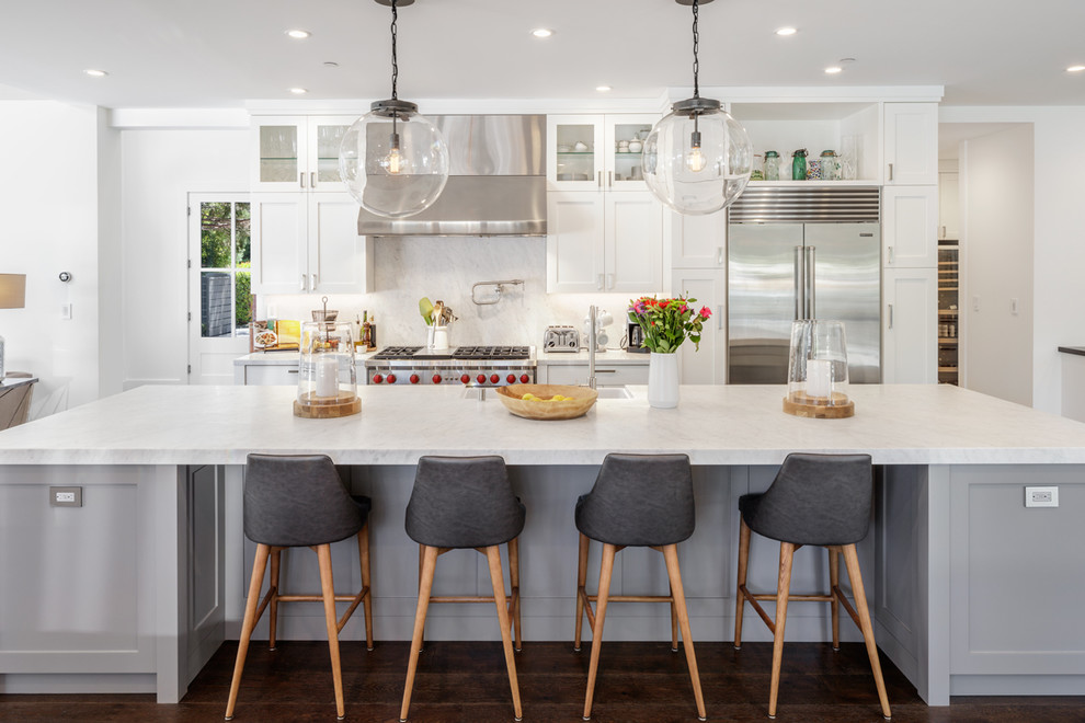 Inspiration for a transitional dark wood floor and brown floor kitchen remodel in San Francisco with shaker cabinets, white cabinets, white backsplash, stone slab backsplash, stainless steel appliances, an island and white countertops