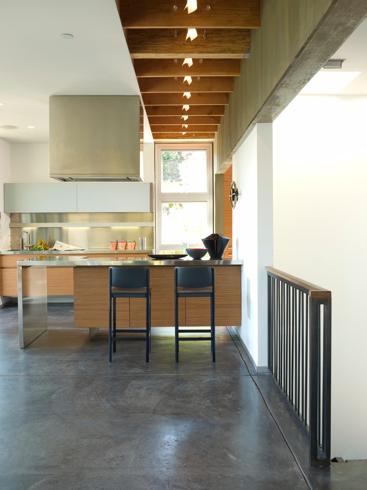 Foto på ett funkis kök, med rostfria vitvaror, bänkskiva i rostfritt stål, stänkskydd med metallisk yta och stänkskydd i metallkakel