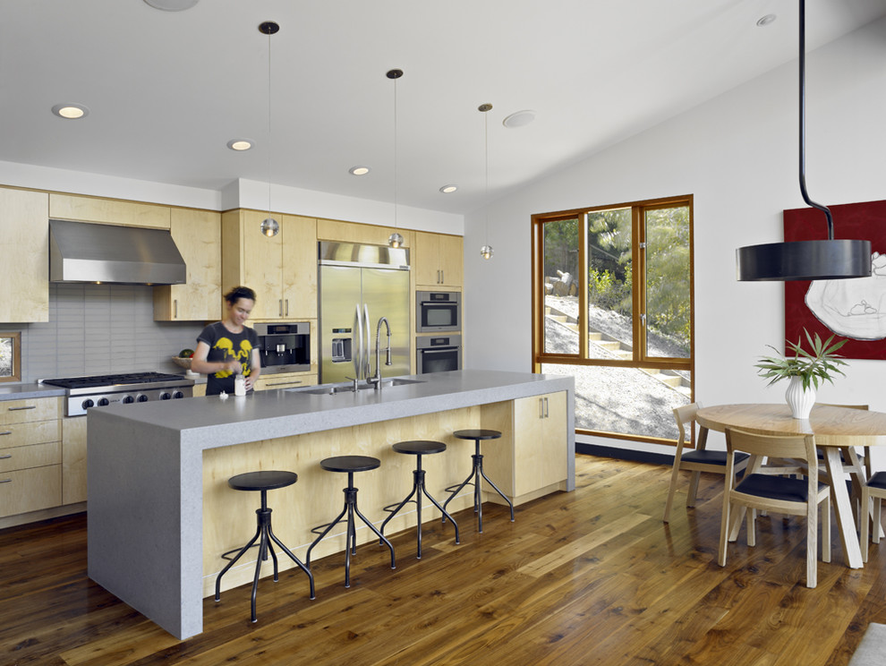 Moderne Wohnküche mit Küchengeräten aus Edelstahl, flächenbündigen Schrankfronten, hellen Holzschränken, Quarzwerkstein-Arbeitsplatte und Küchenrückwand in Grau in San Francisco