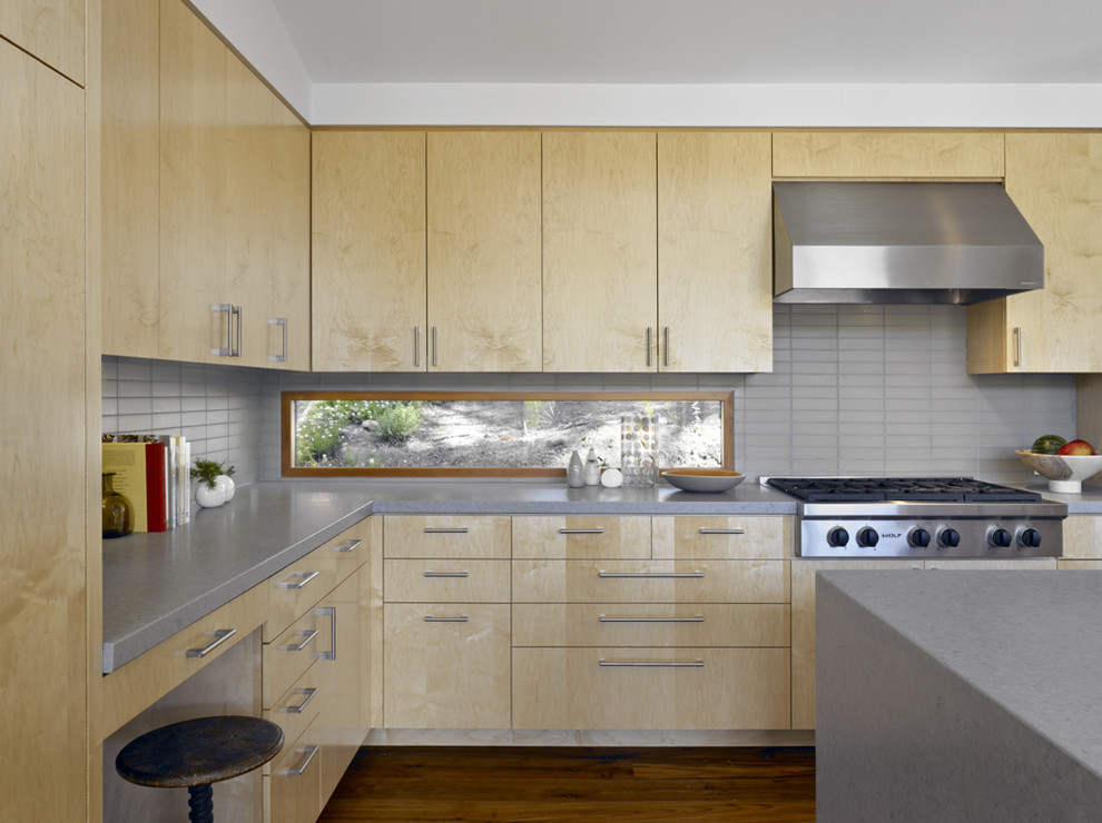 Inspiration pour une grande cuisine minimaliste en bois clair avec un électroménager en acier inoxydable, un placard à porte plane, une crédence grise, un plan de travail en quartz modifié, un sol en bois brun, îlot et un plan de travail gris.