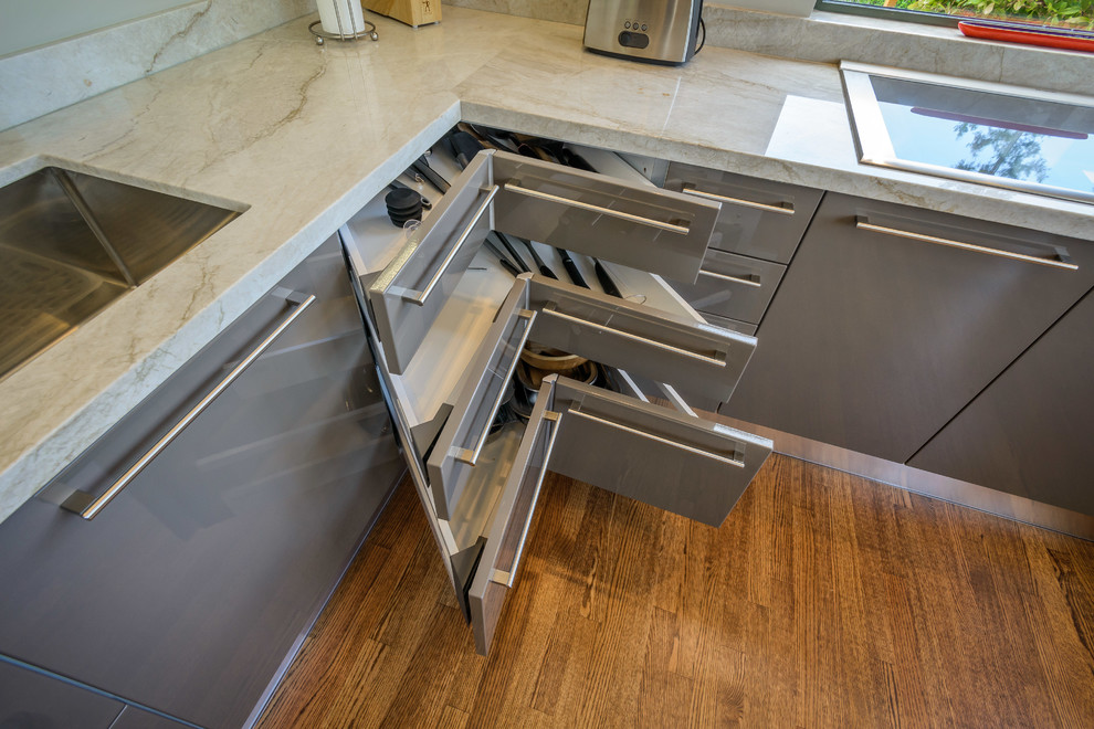 This is an example of a large modern grey and cream u-shaped kitchen in San Francisco with a built-in sink, flat-panel cabinets, grey cabinets, granite worktops, stainless steel appliances and medium hardwood flooring.
