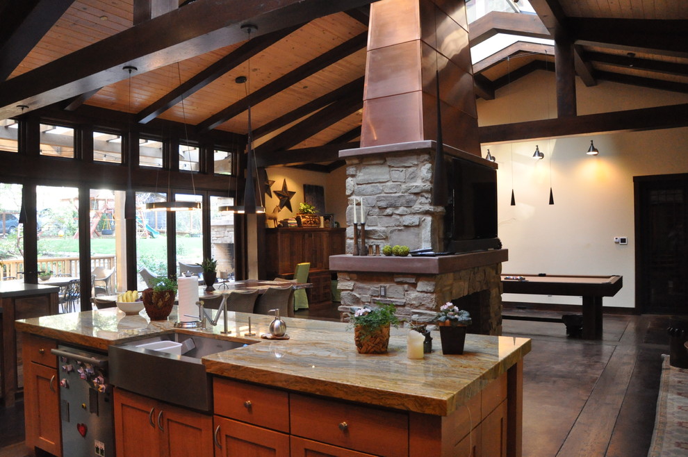 Foto på ett stort rustikt brun kök, med en rustik diskho, släta luckor, skåp i mellenmörkt trä, granitbänkskiva, brunt stänkskydd, stänkskydd i stenkakel, integrerade vitvaror, betonggolv, en köksö och brunt golv