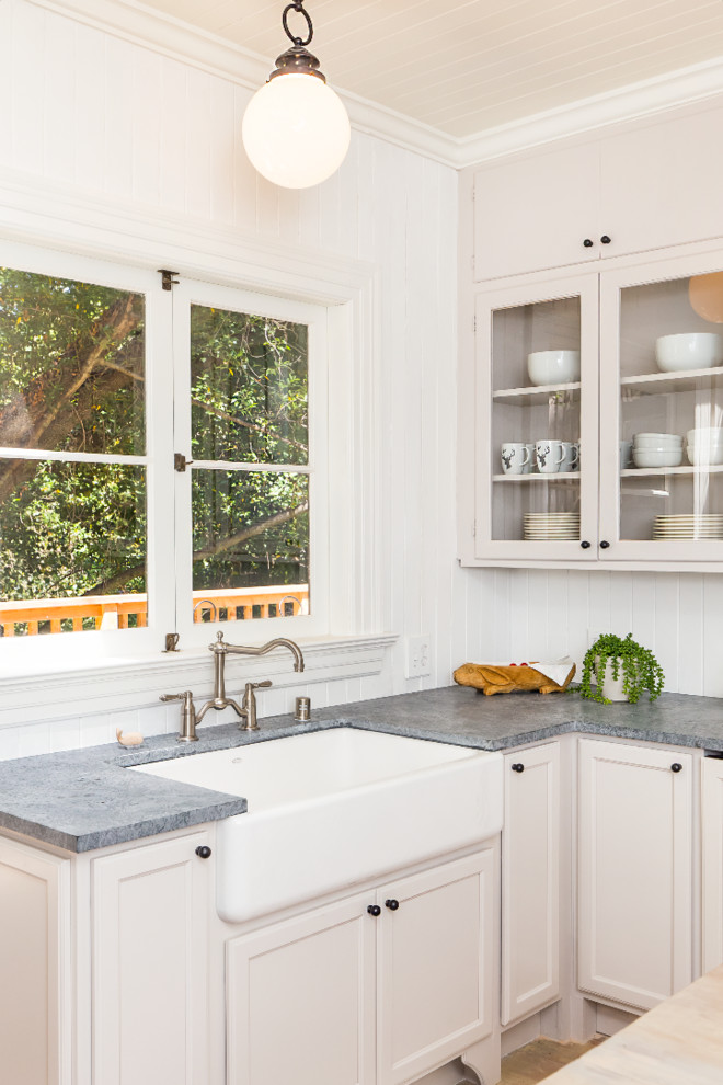 サンフランシスコにある小さなラスティックスタイルのおしゃれなキッチン (エプロンフロントシンク、中間色木目調キャビネット、白いキッチンパネル、木材のキッチンパネル、白い調理設備、淡色無垢フローリング) の写真