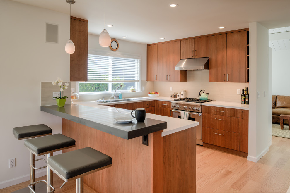 Mid-sized 1950s u-shaped light wood floor and beige floor kitchen photo in San Francisco with flat-panel cabinets, medium tone wood cabinets, a peninsula, an undermount sink, stainless steel appliances and white countertops