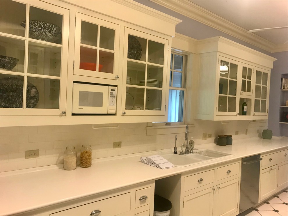 Exempel på ett avskilt, mellanstort klassiskt vit linjärt vitt kök, med en trippel diskho, luckor med glaspanel, vita skåp, bänkskiva i kvarts, vitt stänkskydd, stänkskydd i tunnelbanekakel, klinkergolv i porslin och flerfärgat golv