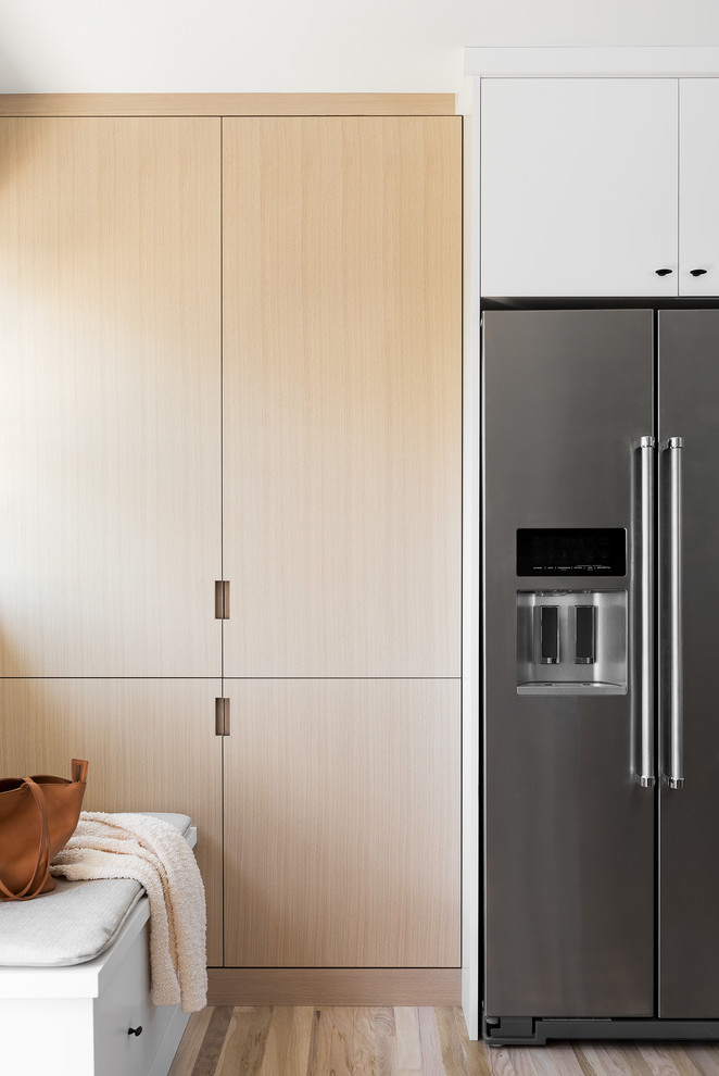 Photo of a small scandinavian l-shaped kitchen/diner in Salt Lake City with a belfast sink, flat-panel cabinets, light wood cabinets, engineered stone countertops, grey splashback, marble splashback, stainless steel appliances, light hardwood flooring, an island, beige floors and grey worktops.