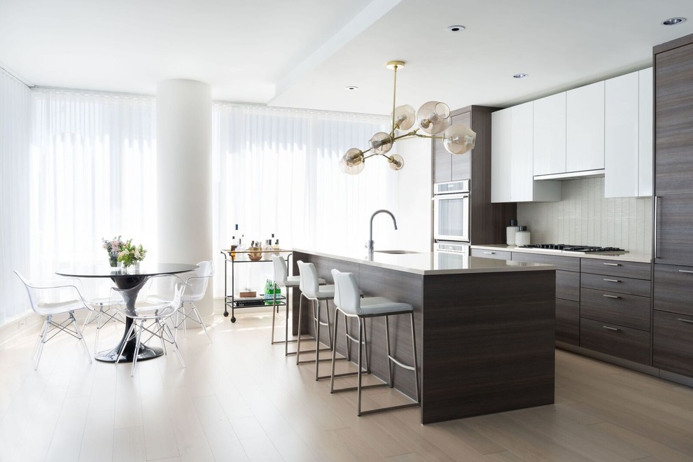 Ejemplo de cocina comedor contemporánea de tamaño medio con fregadero de un seno, armarios con paneles lisos, puertas de armario de madera en tonos medios, salpicadero verde, suelo de madera clara, una isla y encimeras grises