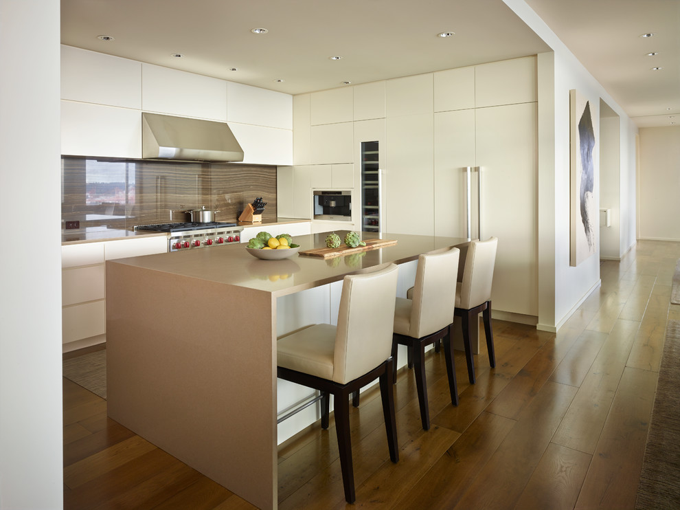 Contemporary l-shaped kitchen in Seattle with flat-panel cabinets, white cabinets, brown splashback, stone slab splashback, integrated appliances, dark hardwood flooring and an island.