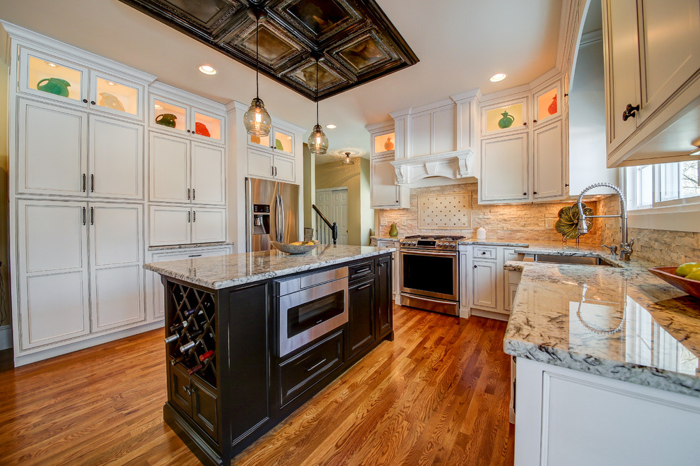 Large cottage u-shaped medium tone wood floor and brown floor eat-in kitchen photo in Dallas with an undermount sink, shaker cabinets, white cabinets, granite countertops, beige backsplash, stone slab backsplash, stainless steel appliances, an island and multicolored countertops
