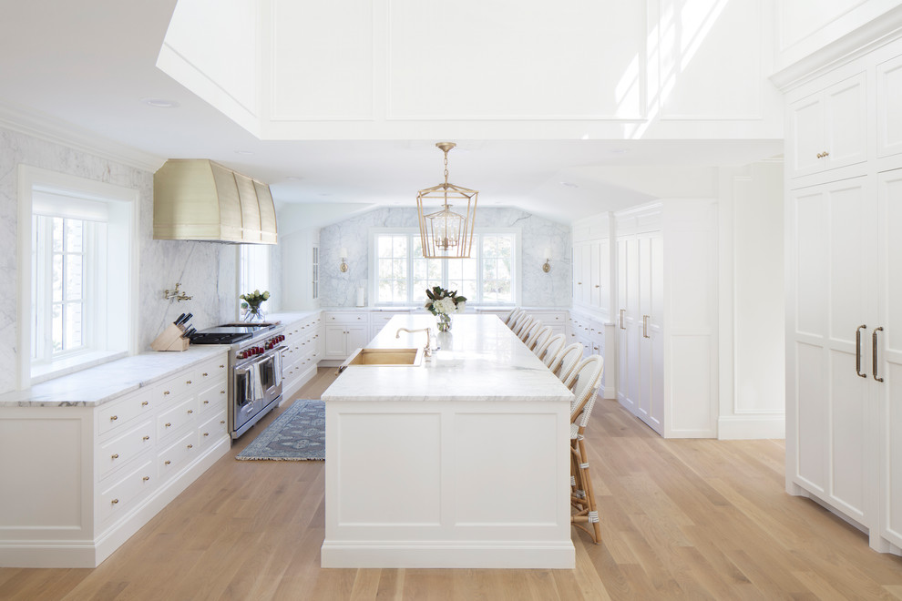 Inspiration for a huge transitional u-shaped light wood floor and brown floor open concept kitchen remodel in Salt Lake City with a farmhouse sink, beaded inset cabinets, white cabinets, marble countertops, white backsplash, marble backsplash, stainless steel appliances and an island