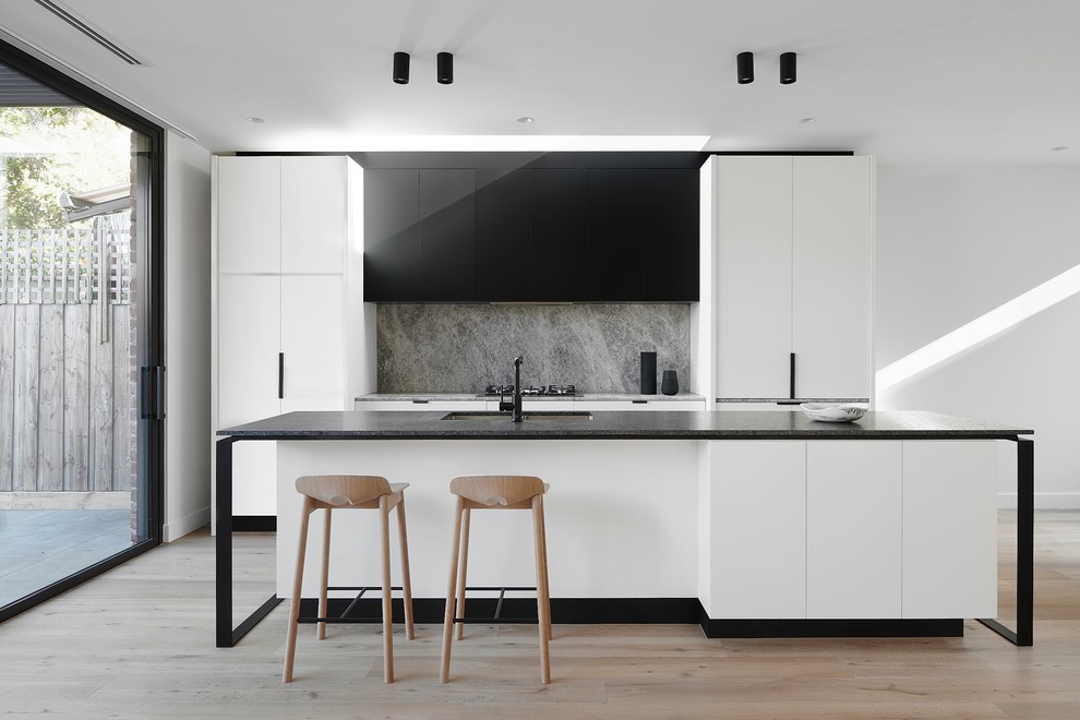 Immagine di una cucina contemporanea con lavello sottopiano, ante lisce, paraspruzzi grigio, elettrodomestici da incasso e parquet chiaro