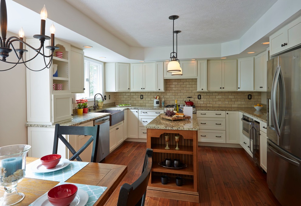 Eat-in kitchen - mid-sized transitional u-shaped medium tone wood floor and brown floor eat-in kitchen idea in Baltimore with a farmhouse sink, flat-panel cabinets, granite countertops, beige backsplash, stone tile backsplash, stainless steel appliances, an island and white cabinets