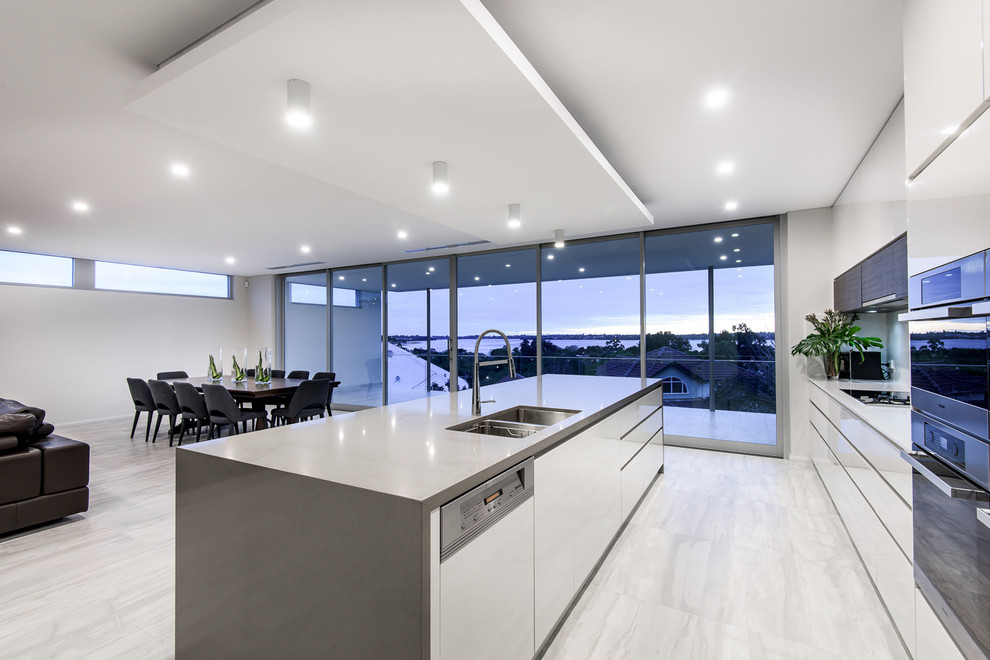 Mid-sized minimalist galley porcelain tile eat-in kitchen photo in Perth with an undermount sink, flat-panel cabinets, white cabinets, quartz countertops, white backsplash, stone slab backsplash, stainless steel appliances and an island