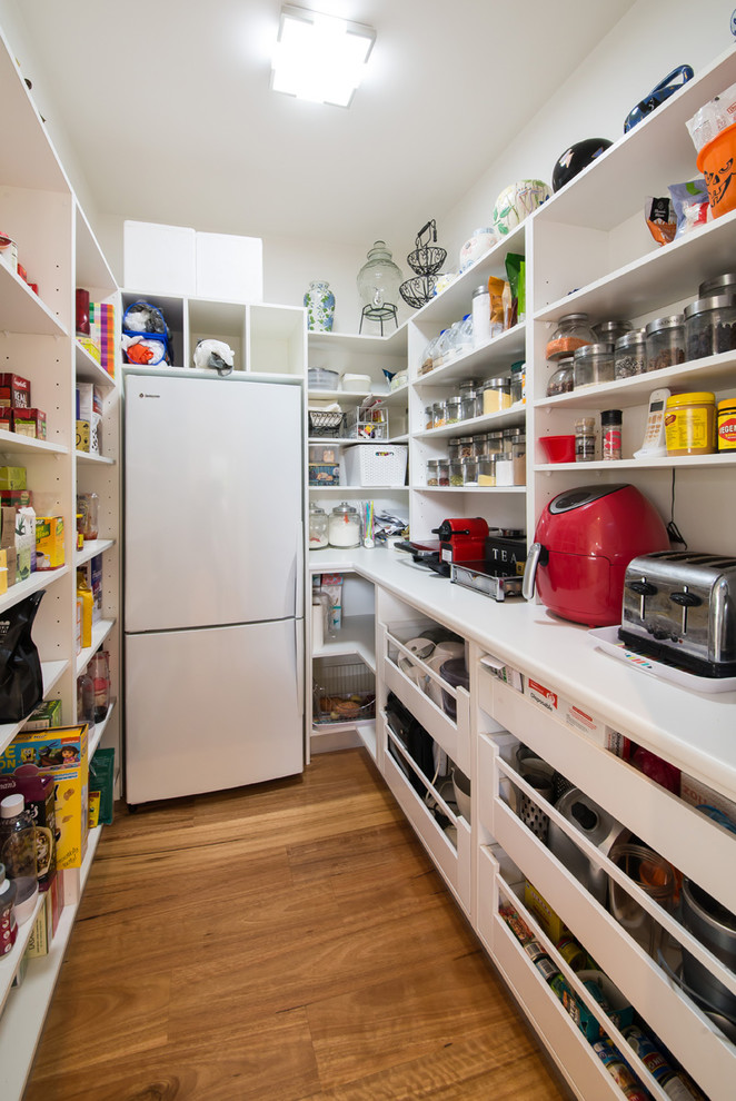 Bild på ett stort funkis kök, med en undermonterad diskho, vita skåp, rostfria vitvaror, mellanmörkt trägolv, brunt golv, öppna hyllor, laminatbänkskiva, vitt stänkskydd och en köksö