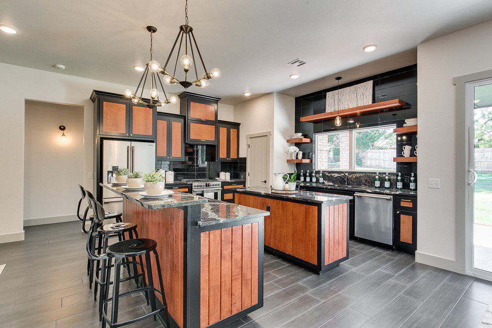 Urban u-shaped gray floor kitchen photo in Oklahoma City with shaker cabinets, medium tone wood cabinets, black backsplash, stainless steel appliances, two islands and gray countertops