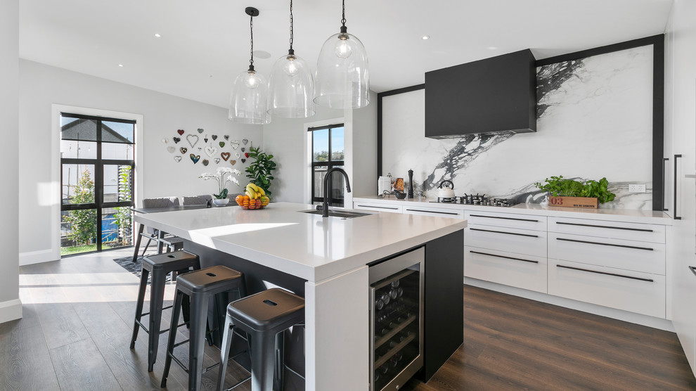 Esempio di una cucina design con lavello sottopiano, ante lisce, paraspruzzi grigio, elettrodomestici da incasso, pavimento in legno massello medio, pavimento marrone e top bianco