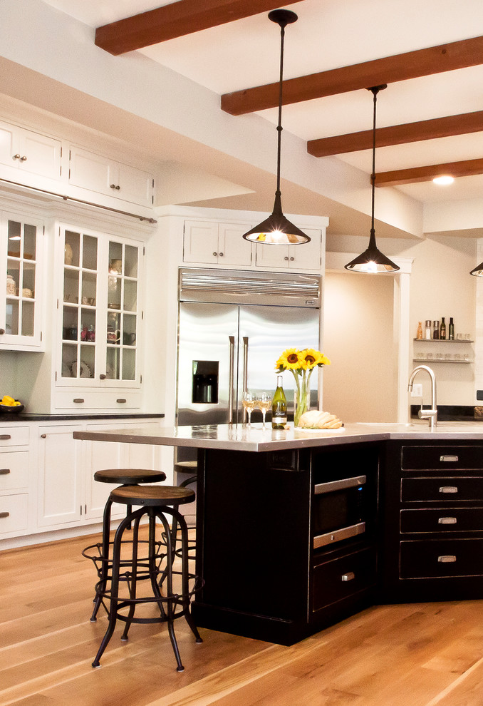 Bild på ett funkis kök, med rostfria vitvaror, bänkskiva i rostfritt stål och svarta skåp