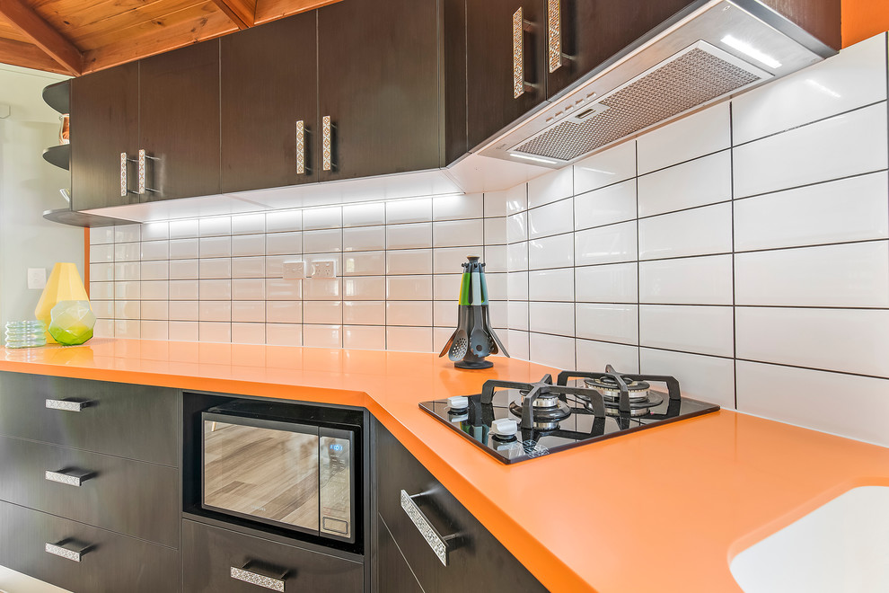 Diseño de cocina lineal moderna pequeña cerrada con fregadero integrado, encimera de acrílico, salpicadero amarillo, salpicadero de azulejos tipo metro y encimeras naranjas