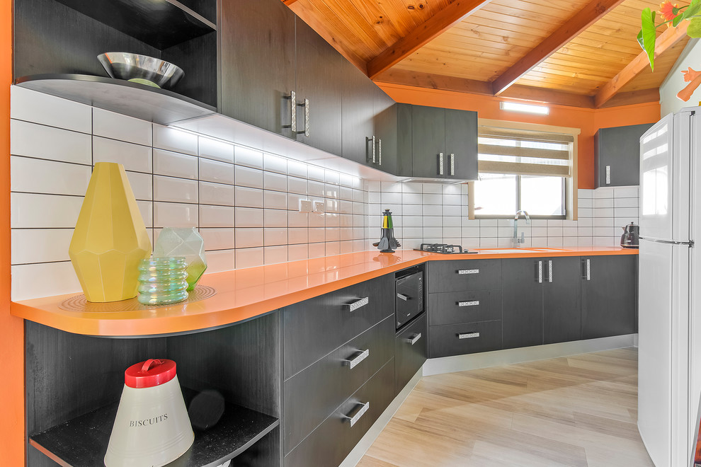Modelo de cocina lineal moderna pequeña cerrada con fregadero integrado, encimera de acrílico, salpicadero amarillo, salpicadero de azulejos tipo metro y encimeras naranjas