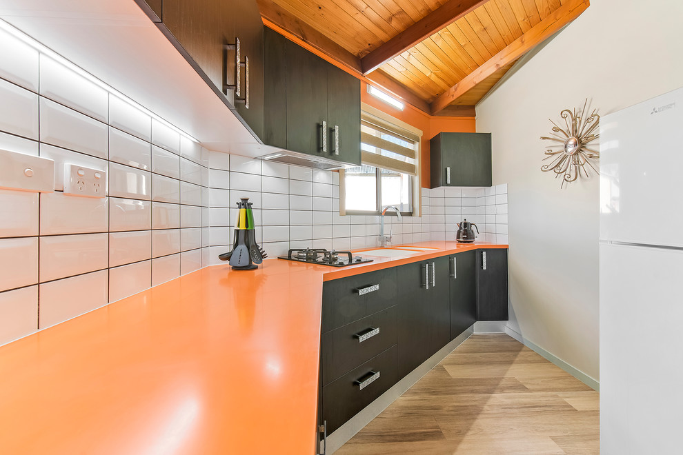 Ejemplo de cocina lineal minimalista pequeña cerrada con fregadero integrado, encimera de acrílico, salpicadero amarillo, salpicadero de azulejos tipo metro y encimeras naranjas